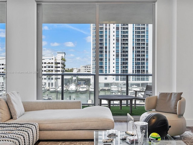 living room with wood-type flooring, a wall of windows, and a water view