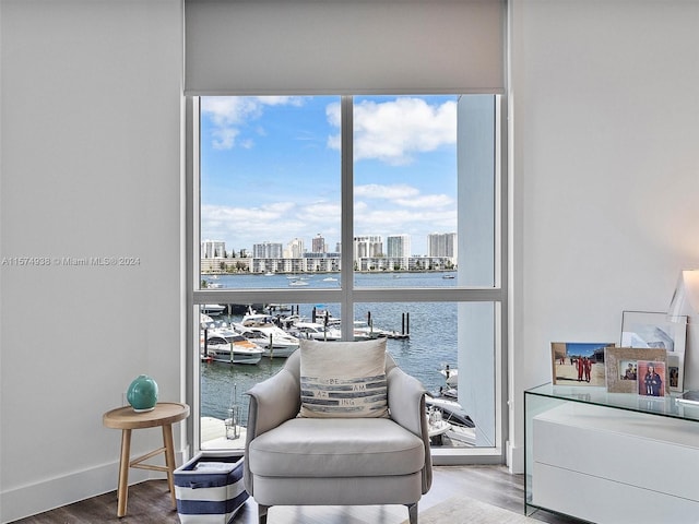 sitting room with expansive windows, a water view, and wood-type flooring