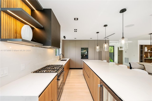 kitchen featuring hanging light fixtures, a spacious island, high end range, sink, and light wood-type flooring