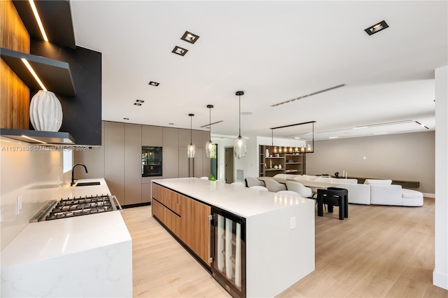 kitchen with a spacious island, range, light wood-type flooring, beverage cooler, and sink