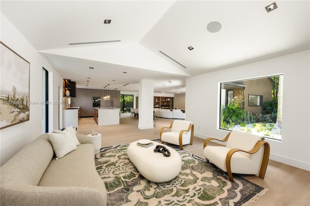 living room with lofted ceiling, light wood-type flooring, and plenty of natural light