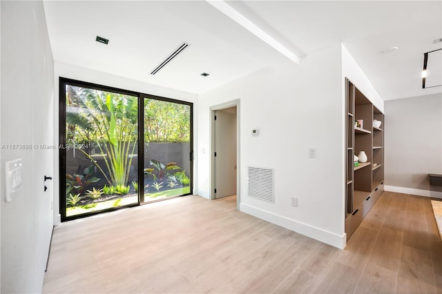 spare room featuring light hardwood / wood-style floors and beam ceiling