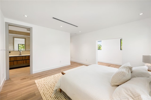 bedroom with ensuite bath and light hardwood / wood-style floors