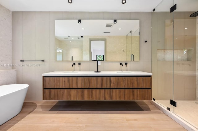 bathroom with tile walls, plus walk in shower, dual bowl vanity, and tile flooring