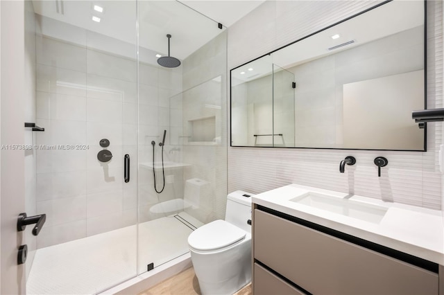 bathroom with tile walls, an enclosed shower, vanity, and toilet