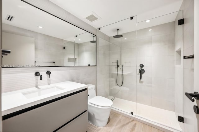 bathroom featuring tile walls, hardwood / wood-style floors, an enclosed shower, toilet, and vanity