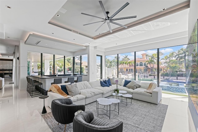 tiled living room with plenty of natural light, ceiling fan, and a tray ceiling