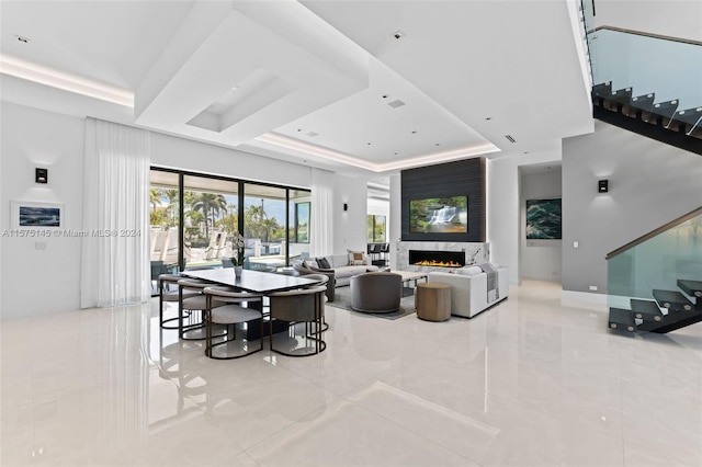 living room featuring a raised ceiling, light tile floors, and a fireplace