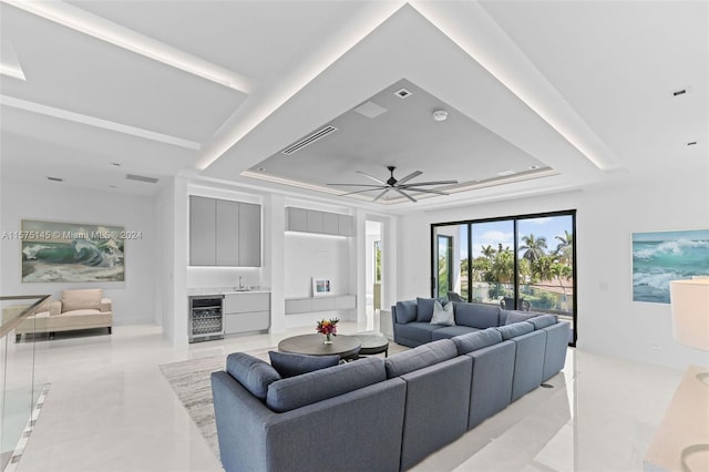 tiled living room featuring ceiling fan, beverage cooler, and a tray ceiling