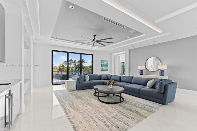 living room featuring ceiling fan, light tile floors, and a tray ceiling