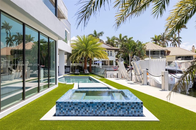 view of home's community featuring a patio area, a lawn, and a swimming pool with hot tub