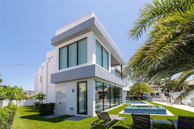 rear view of property featuring a fenced in pool, a patio, a balcony, and a lawn