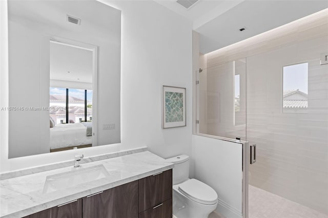 bathroom featuring vanity with extensive cabinet space, a shower with door, and toilet