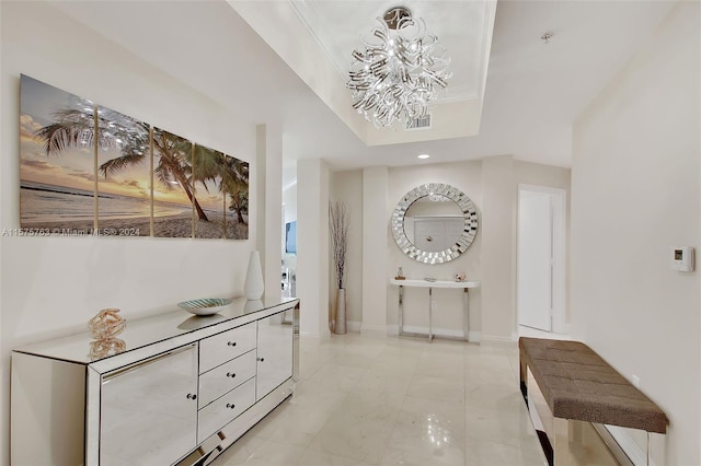 hall featuring an inviting chandelier, light tile floors, and a tray ceiling