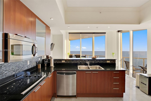 kitchen featuring appliances with stainless steel finishes, a water view, sink, light tile flooring, and dark stone countertops