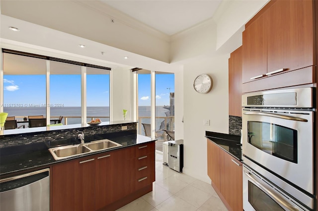 kitchen with sink, appliances with stainless steel finishes, dark stone counters, and light tile floors