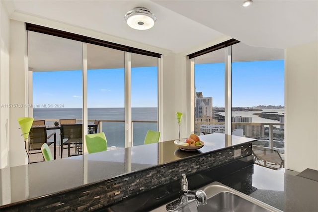 kitchen featuring a water view, a wealth of natural light, dark stone counters, and expansive windows