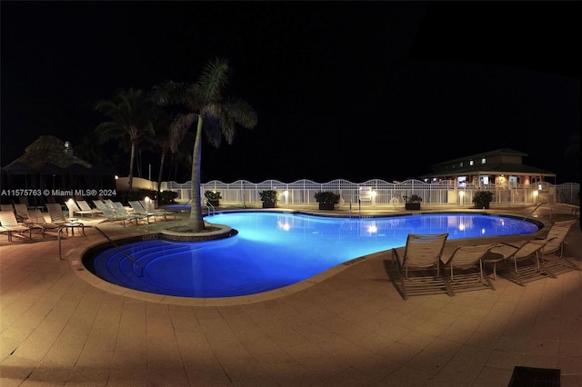 pool at night featuring a patio area