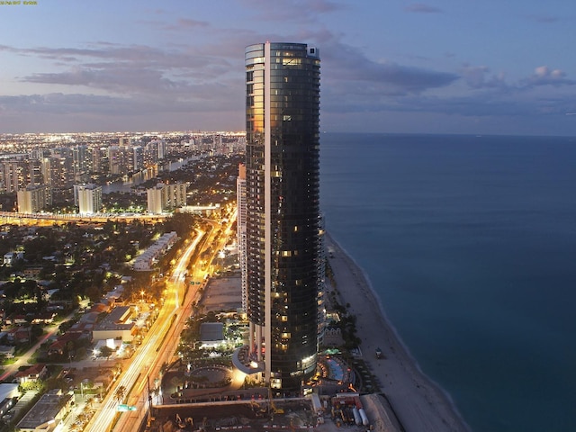 aerial view at dusk with a view of the beach and a water view