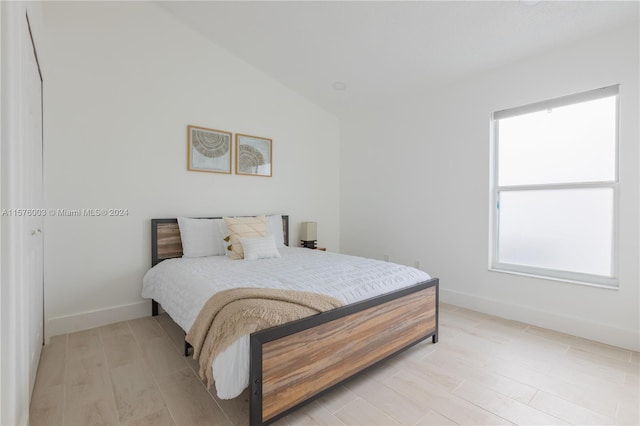 bedroom with light wood-type flooring and vaulted ceiling