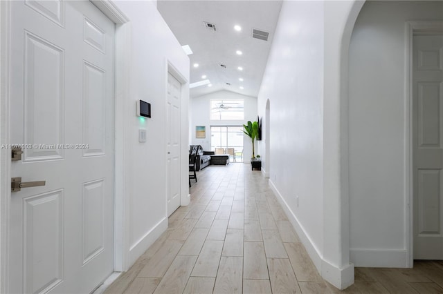 hall with light hardwood / wood-style flooring and lofted ceiling