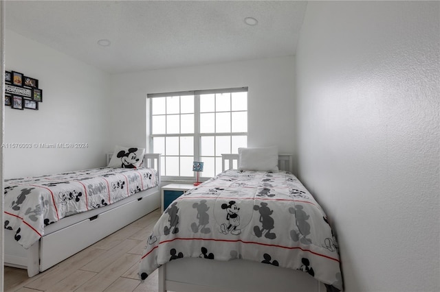 bedroom with light hardwood / wood-style floors and a textured ceiling