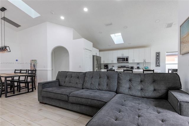 tiled living room with a skylight and high vaulted ceiling