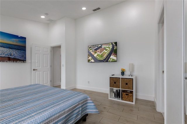 bedroom featuring light hardwood / wood-style floors and a towering ceiling