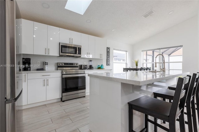 kitchen with stainless steel appliances, a healthy amount of sunlight, and white cabinets