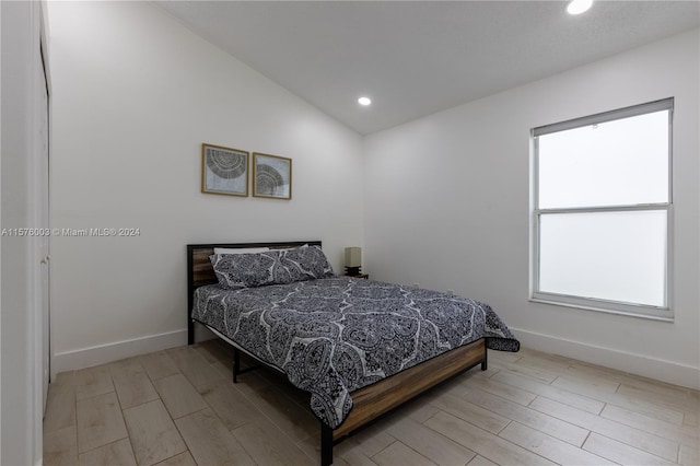 bedroom featuring light hardwood / wood-style floors, vaulted ceiling, and multiple windows