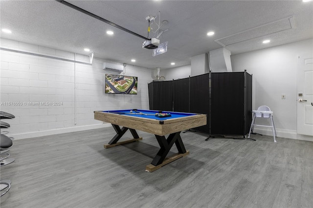 rec room featuring an AC wall unit, light hardwood / wood-style floors, pool table, and a textured ceiling