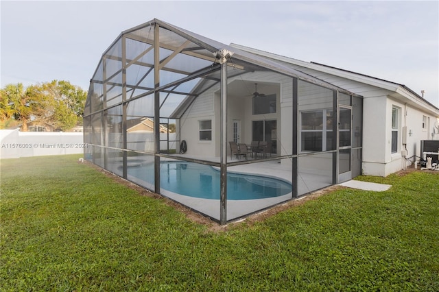 back of property with ceiling fan, a lawn, a fenced in pool, and a lanai