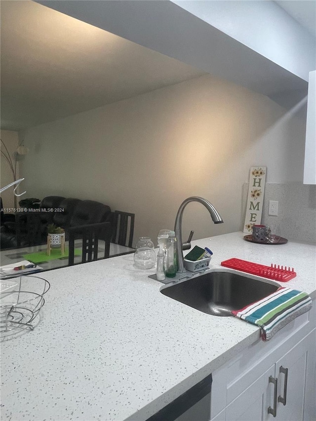 kitchen featuring sink, white cabinetry, and light stone counters