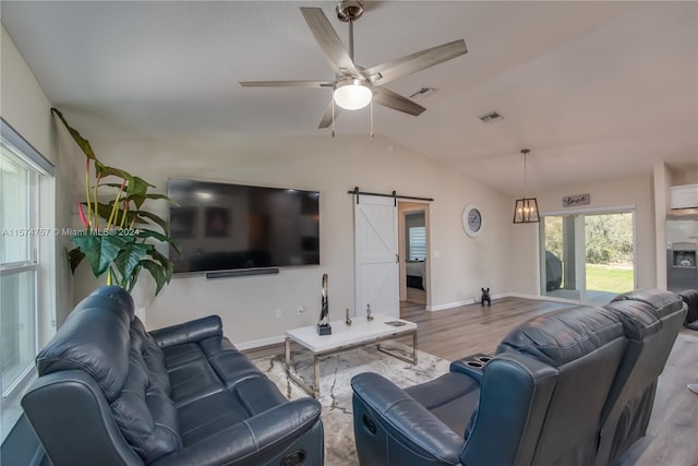 living room featuring lofted ceiling, hardwood / wood-style floors, ceiling fan, and a barn door