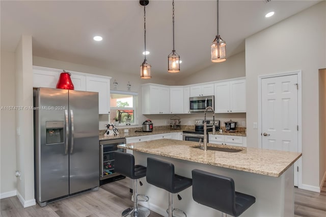 kitchen with appliances with stainless steel finishes, light wood-type flooring, an island with sink, and white cabinetry