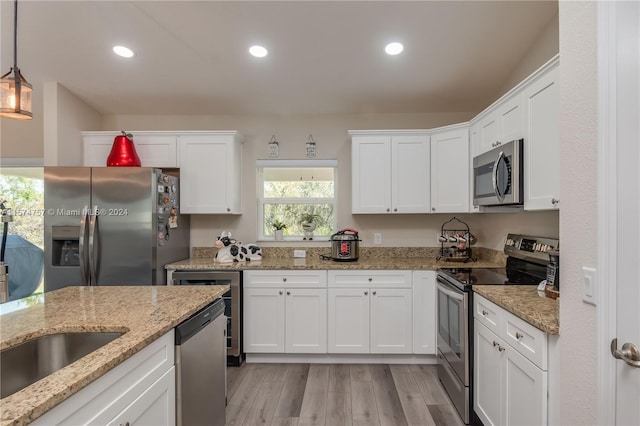 kitchen with decorative light fixtures, light hardwood / wood-style flooring, white cabinetry, stainless steel appliances, and light stone counters