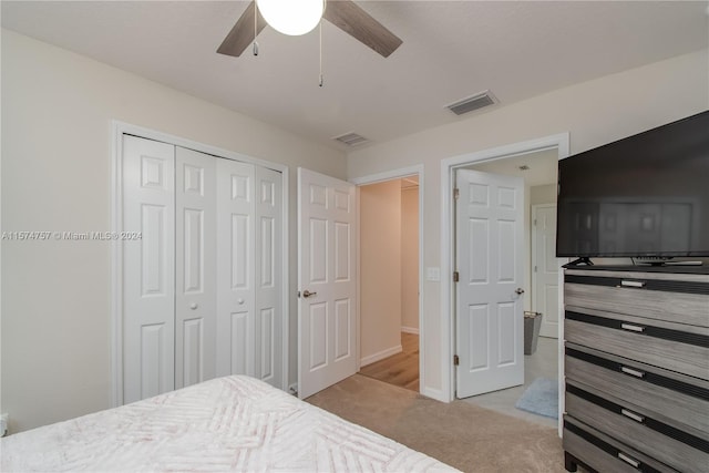 bedroom with light colored carpet, ceiling fan, and a closet