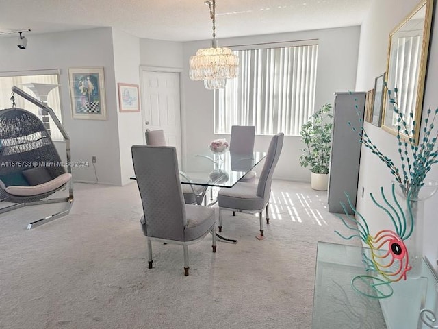 dining space featuring an inviting chandelier, a textured ceiling, and carpet floors