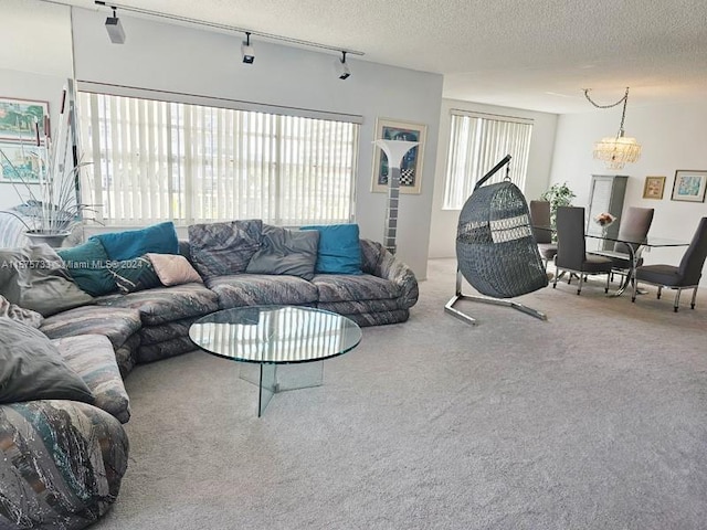 carpeted living room featuring track lighting, a textured ceiling, a wealth of natural light, and a chandelier