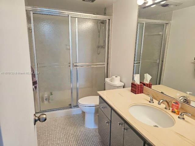 bathroom with tile flooring, a shower with shower door, toilet, and vanity