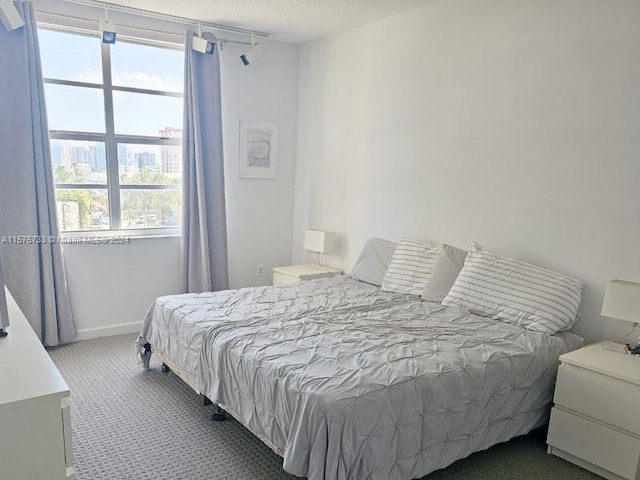 bedroom featuring dark colored carpet and a textured ceiling