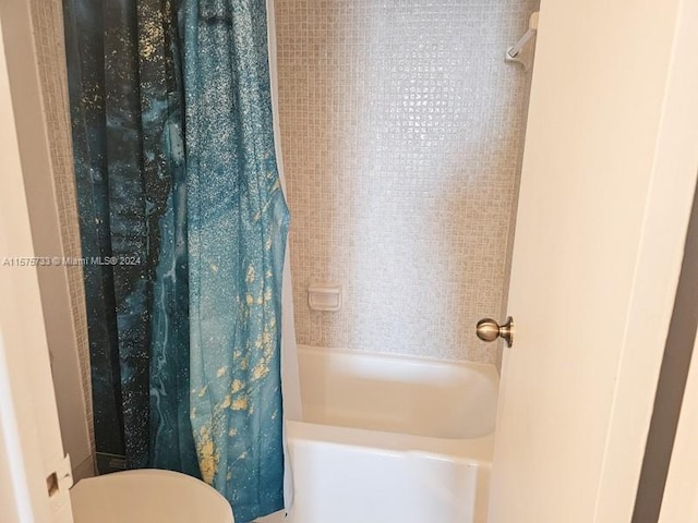 bathroom featuring shower / bathtub combination with curtain and toilet