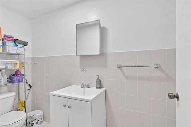 bathroom featuring vanity with extensive cabinet space, toilet, and tile walls