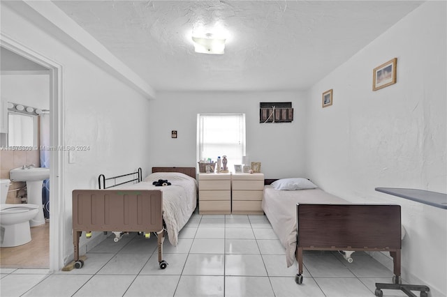 bedroom with connected bathroom, sink, and light tile flooring