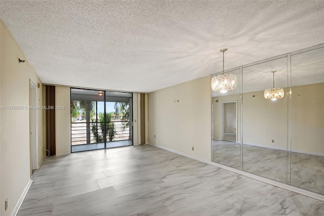 spare room featuring expansive windows, a textured ceiling, and a notable chandelier