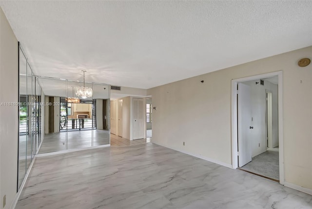 empty room with a textured ceiling and a chandelier