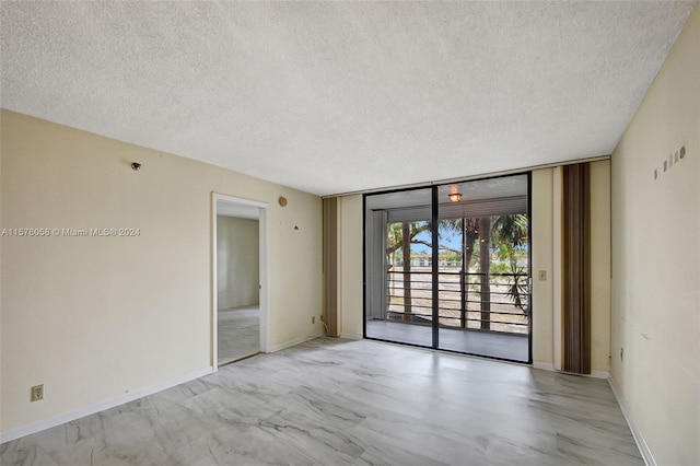 empty room with a textured ceiling and floor to ceiling windows