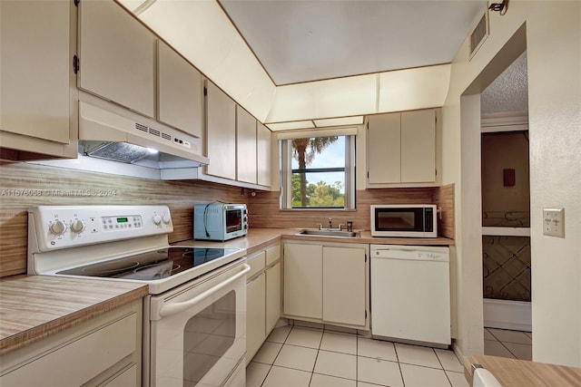 kitchen featuring cream cabinets, tasteful backsplash, light tile patterned floors, sink, and white appliances