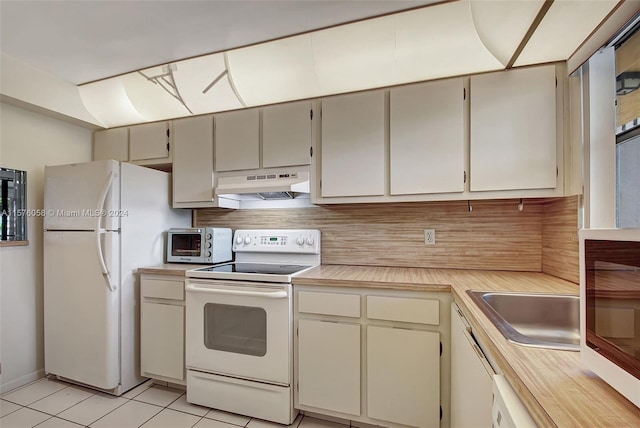 kitchen with white appliances, backsplash, cream cabinets, and light tile patterned floors