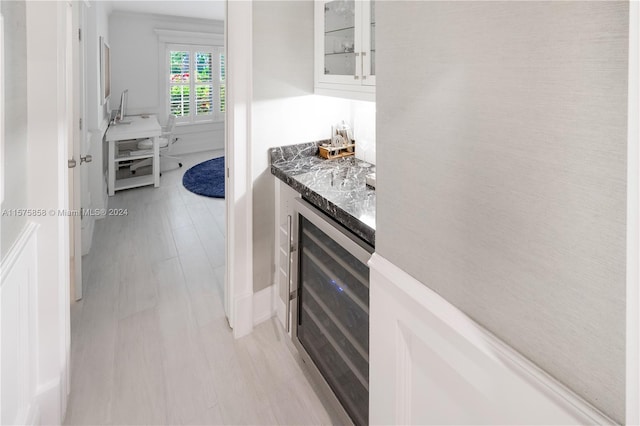 kitchen featuring wine cooler, light hardwood / wood-style floors, white cabinets, and stone countertops